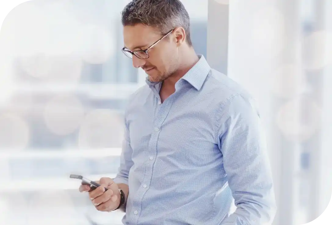 Homem de perfil olhando para o celular enquanto opera via app