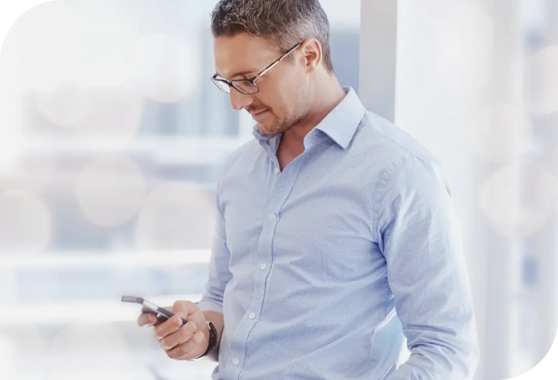 Homem de perfil olhando para o celular enquanto opera via app